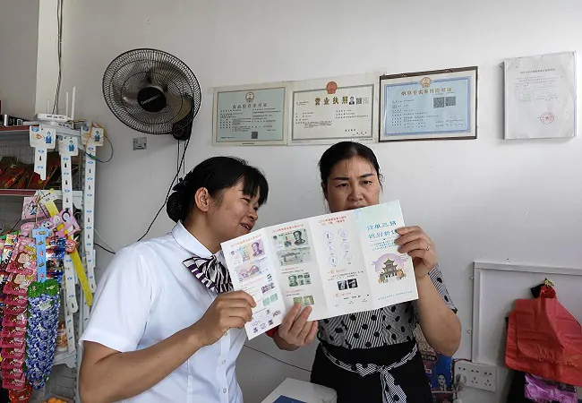 图为：曙光支行工作人员向搬迁点服务点商户讲解假币识别方法.jpg