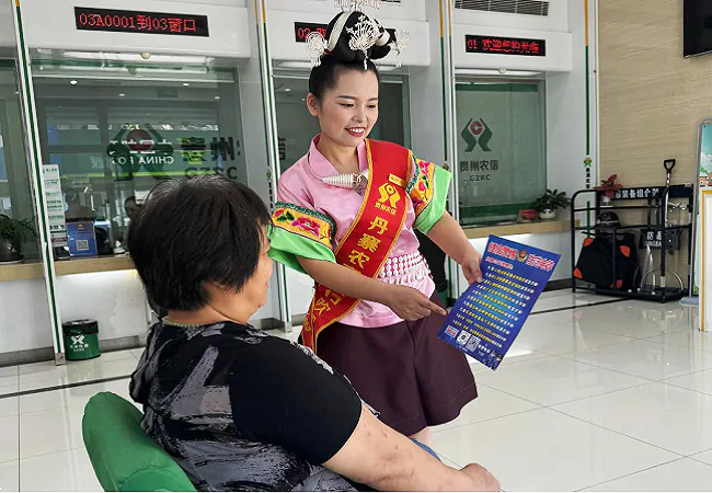 (图为:丹寨农商银行大堂经理身着民族服饰宣传反诈知识).png