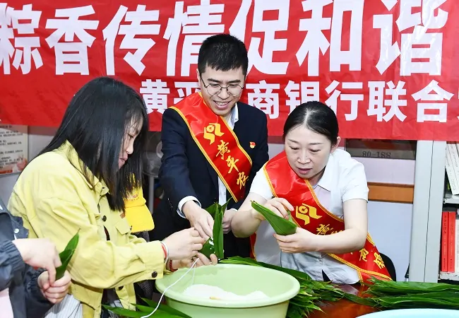 图为:银行工作人员为社区居民包粽子.jpg