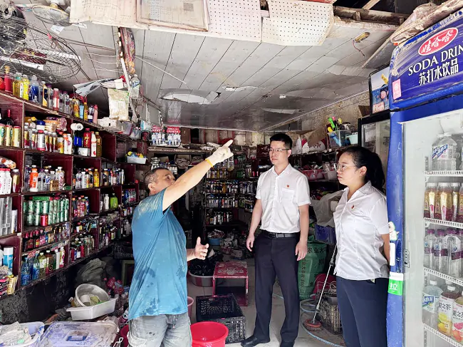图为：该行工作人员走访问需受灾商户.png
