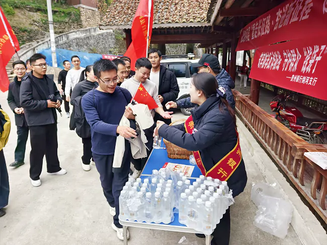 图为:贵州银行工作人员为徒步者免费发放矿泉水并普及反诈金融知识1.png