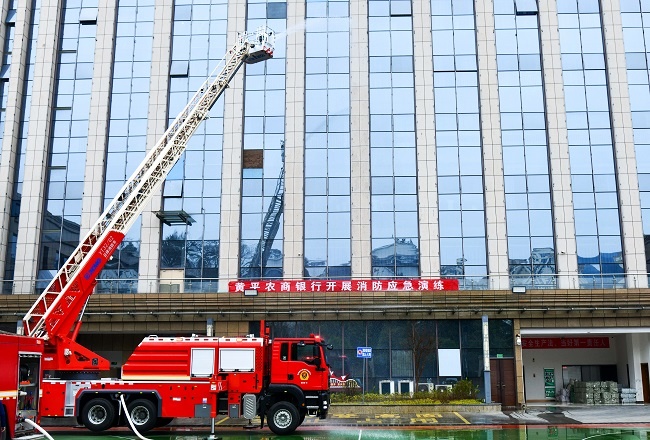 1769676805564535.jpg 图为:演练现场,举高喷射消防车伸展臂架至高空,对准大楼着火区域精准喷水灭火,构建起外部控火防线.jpg