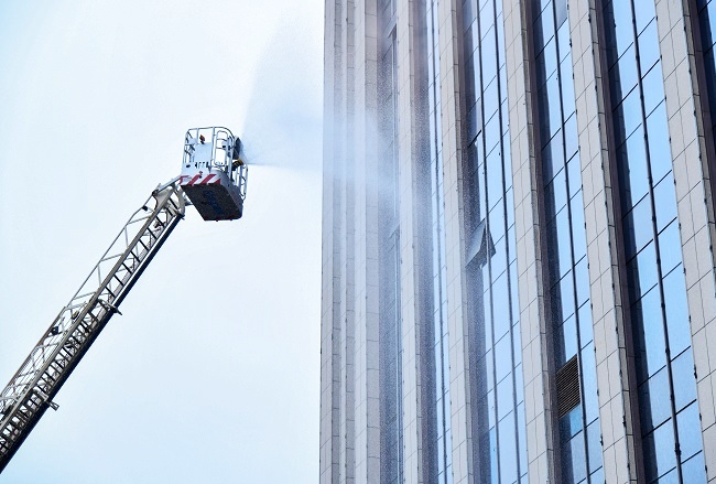 1769676815700964.jpg 图为:演练现场,举高喷射消防车伸展臂架至高空,对准大楼着火区域精准喷水灭火,构建起外部控火防线2.jpg