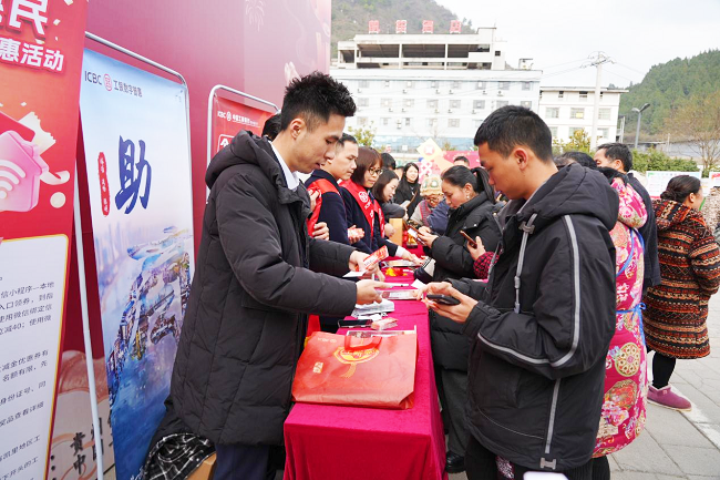 1770247003260772.png 图为:活动现场工作人员为商户推介金融服务产品.png