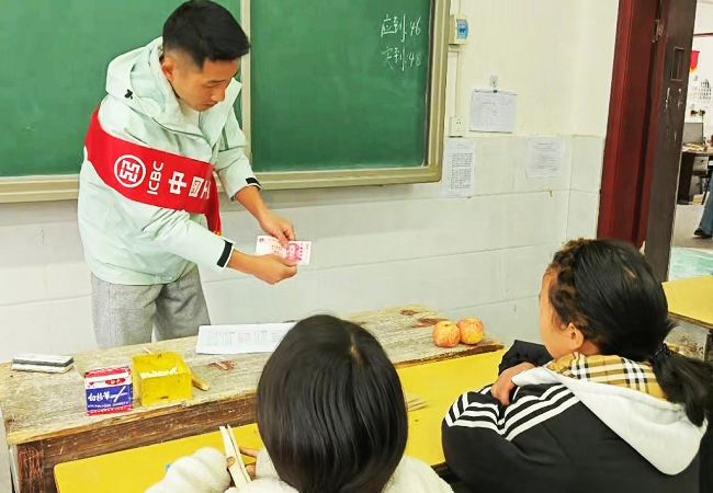 1774602769396430.png 图为:该行驻村干部现场为学生演示假币辨别真伪方法.png