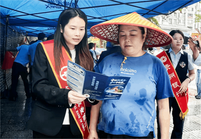 图为：农行工作人员用侗汉双语向当地群众宣讲防非反诈等金融知识.gif